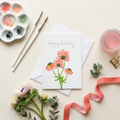 Greeting card with floral watercolour illustration  paint palette, brushes, and flowers on a light background