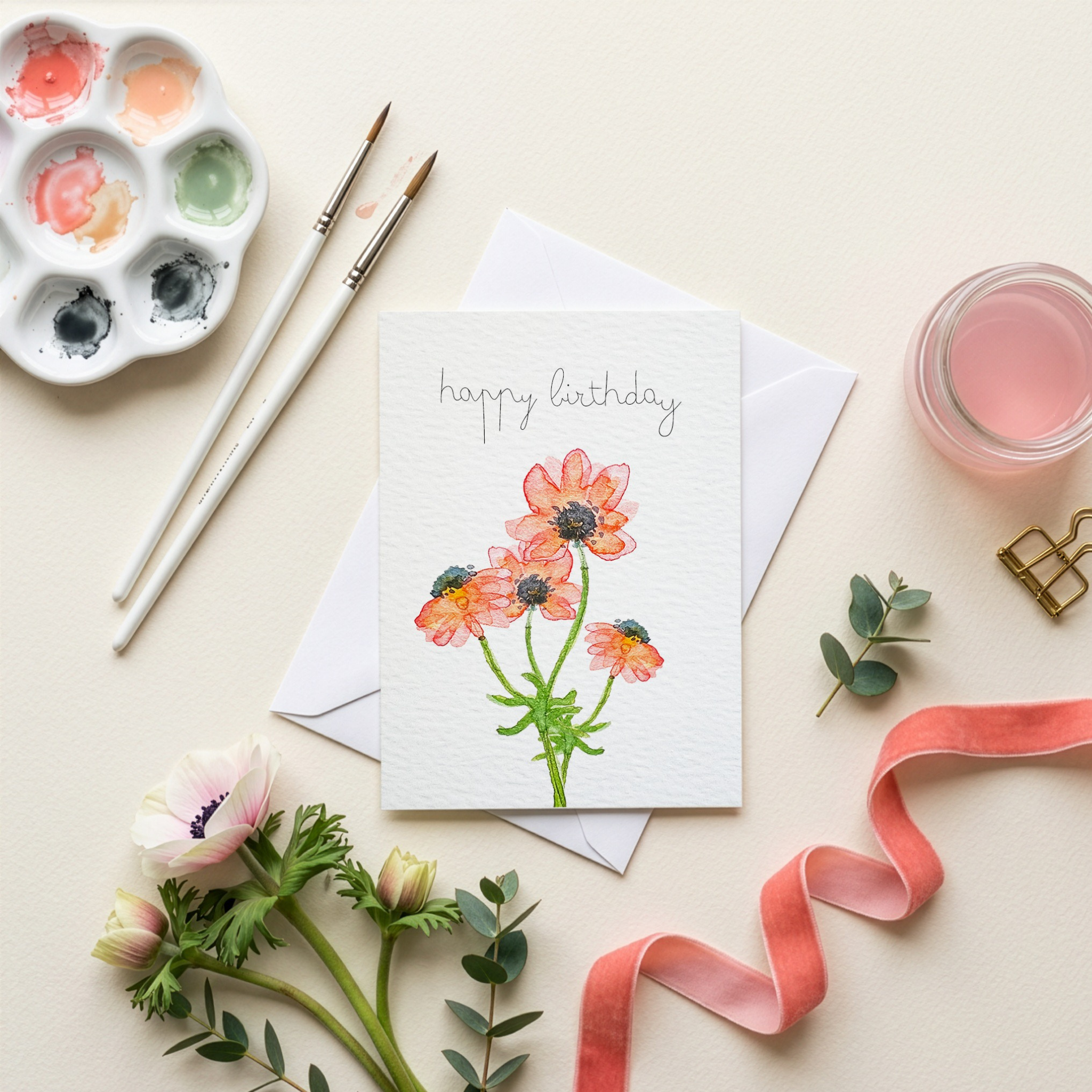 Greeting card with floral watercolour illustration  paint palette, brushes, and flowers on a light background