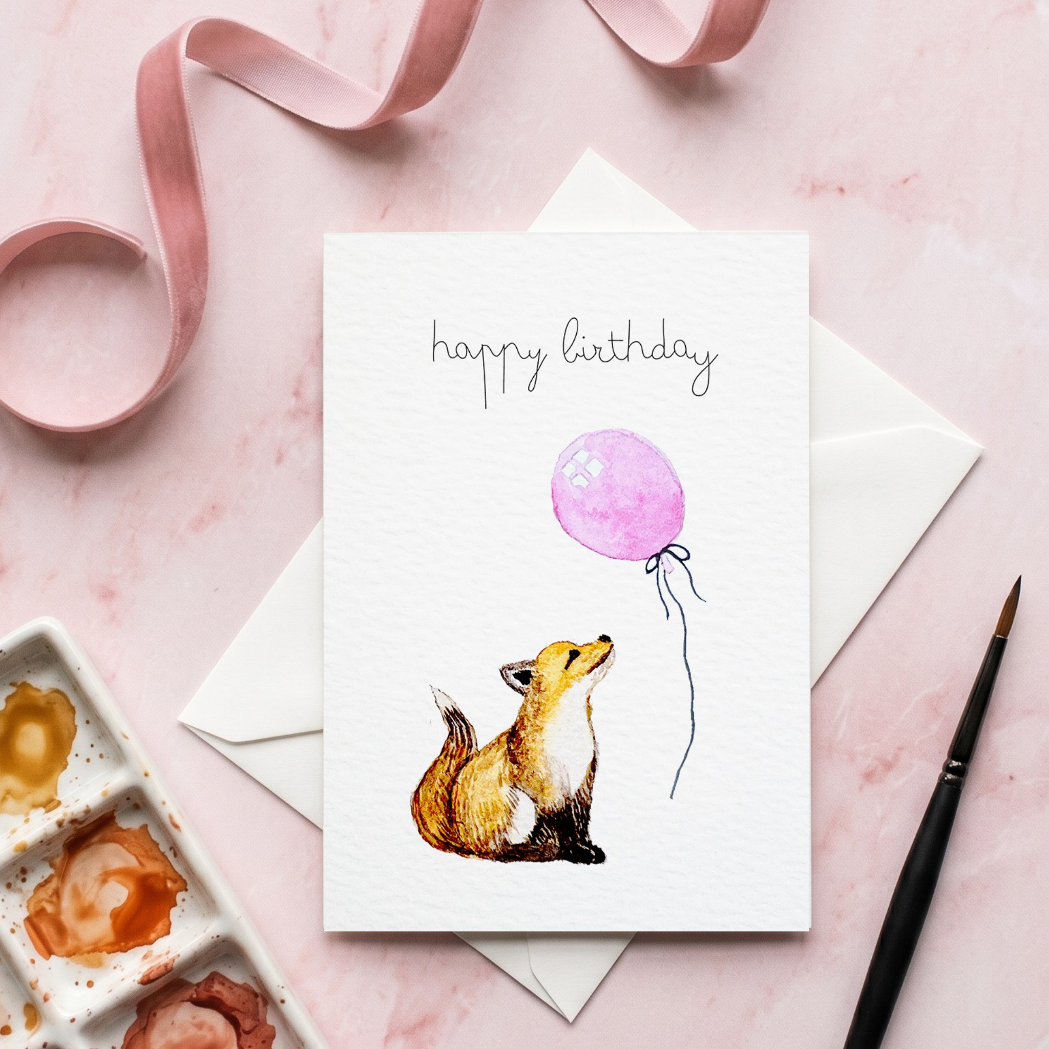 Greeting card with a watercolour illustration of a fox and pink balloon on a pink background