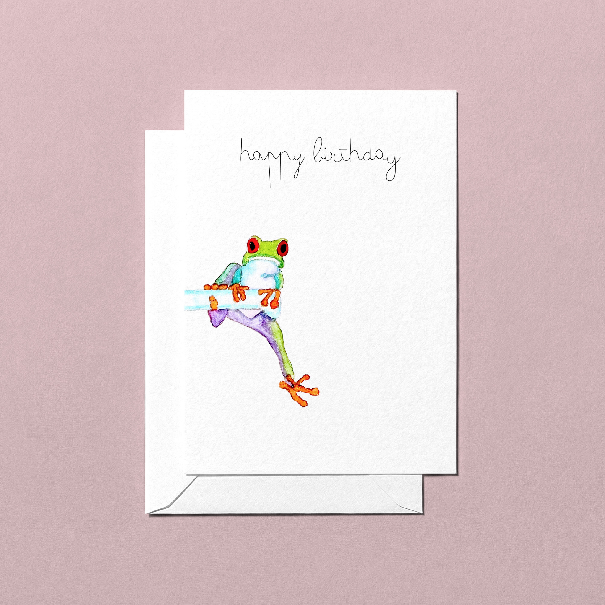 Greeting card with a hand-illustrated watercolour colorful frog illustration and 'happy birthday' text on a pink background