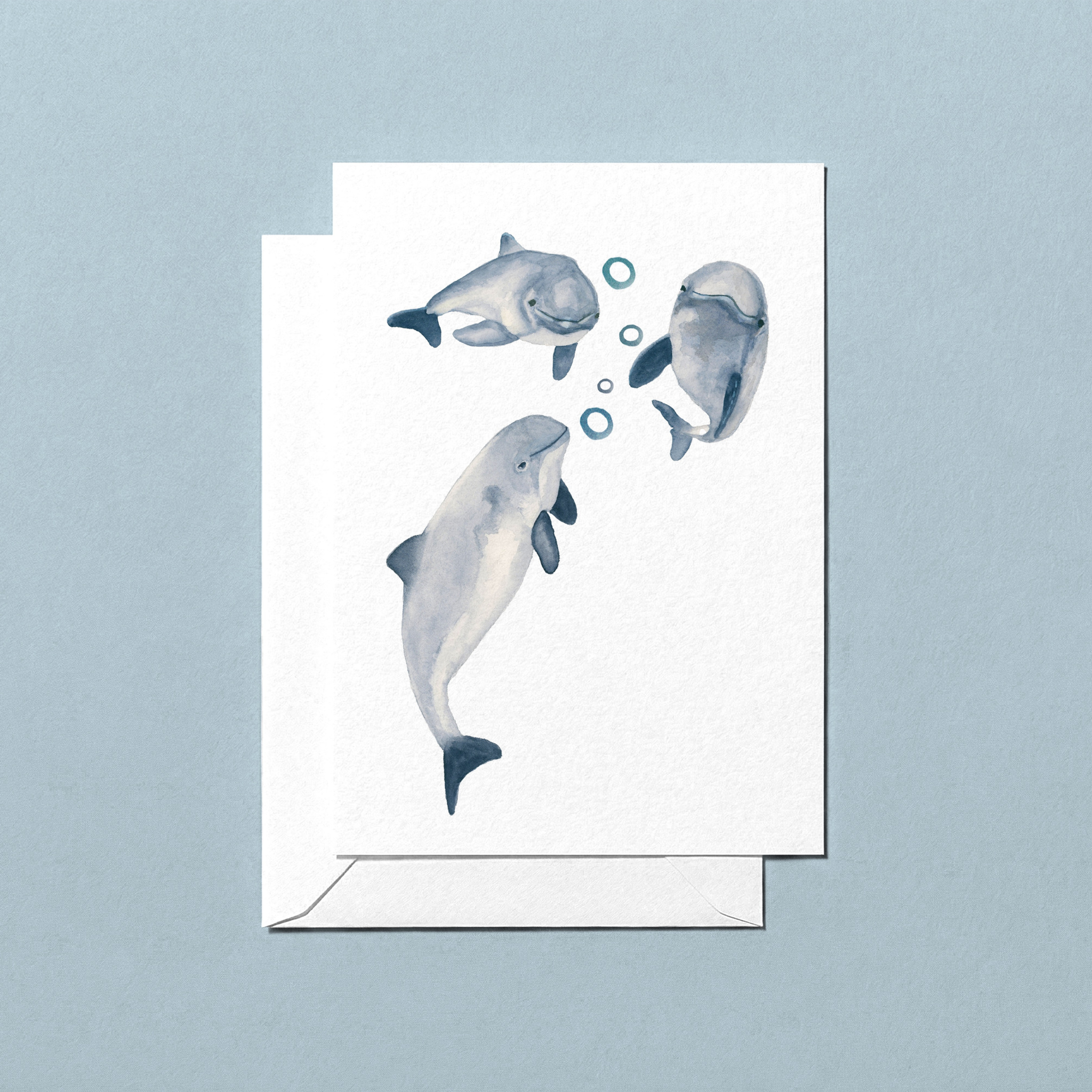 Greeting card with illustrations of three harbour porpoises blowing bubbles on a light blue background