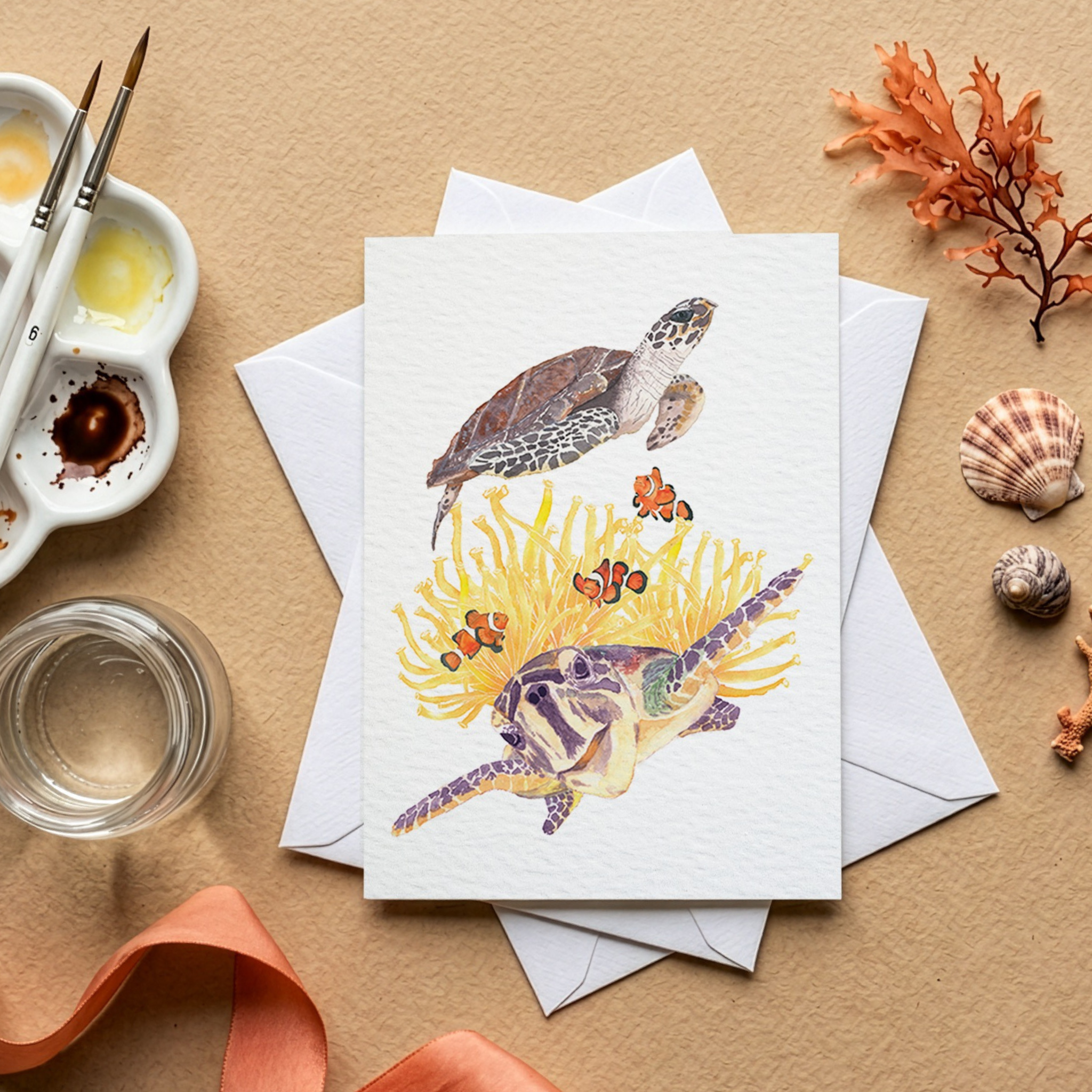 Greeting card with turtle watercolour illustration on a beige surface with art supplies